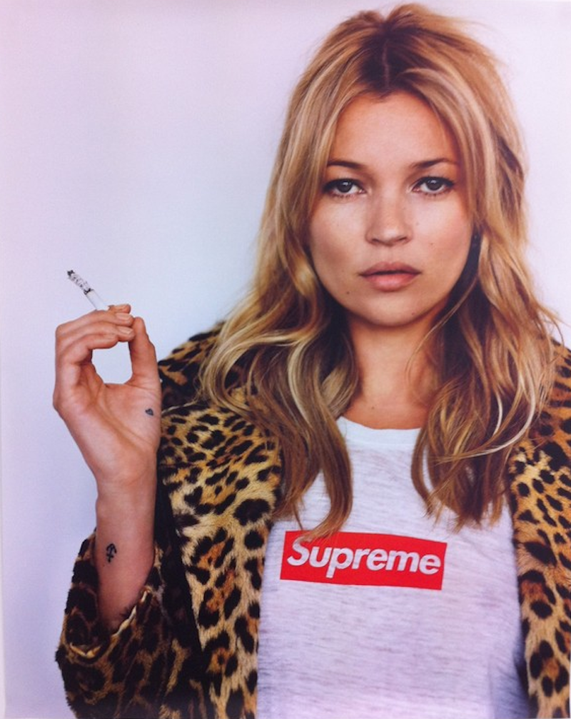 Photo of a woman smoking a cigarette and wearing Supreme clothing